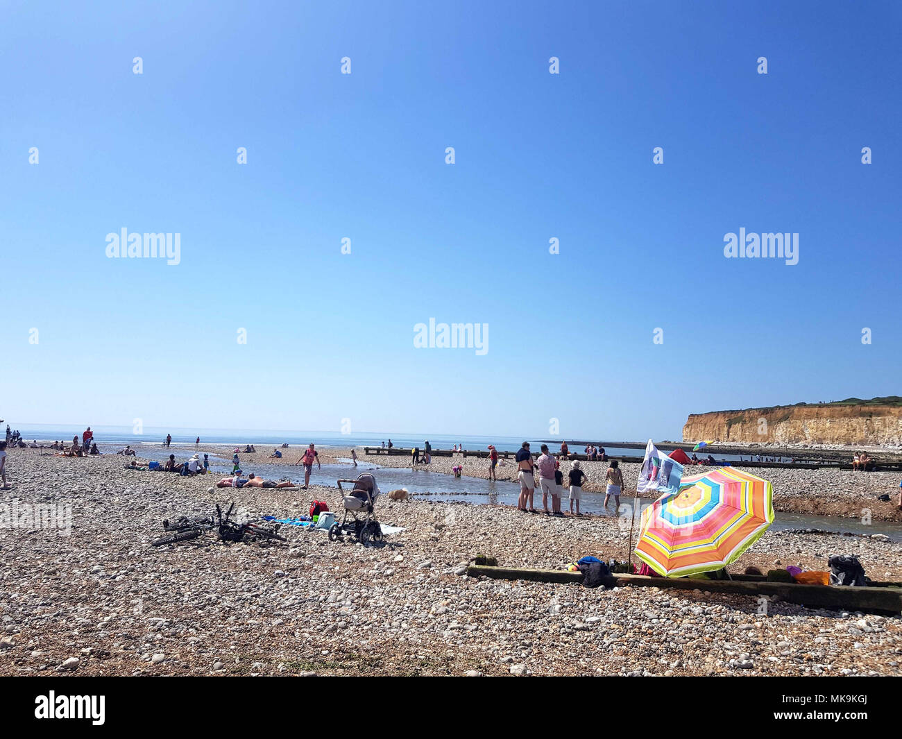 Die Menschen genießen den Strand neben den Sieben Schwestern Klippen in Sussex, als die Bank Holiday Montag dürfte die heißesten werden seit Beginn der Aufzeichnungen. Stockfoto