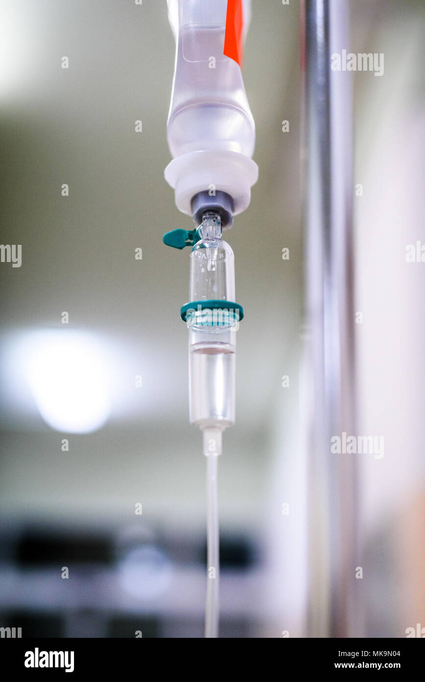 Mit der intravenösen Behandlung iv-Infusion und Flasche auf einer Stange. Flüssige Kochsalzlösung langsam Tropfen Tropfen Drogen, Arzneimittel oder antibiotische Therapie und Chirurgie Stockfoto