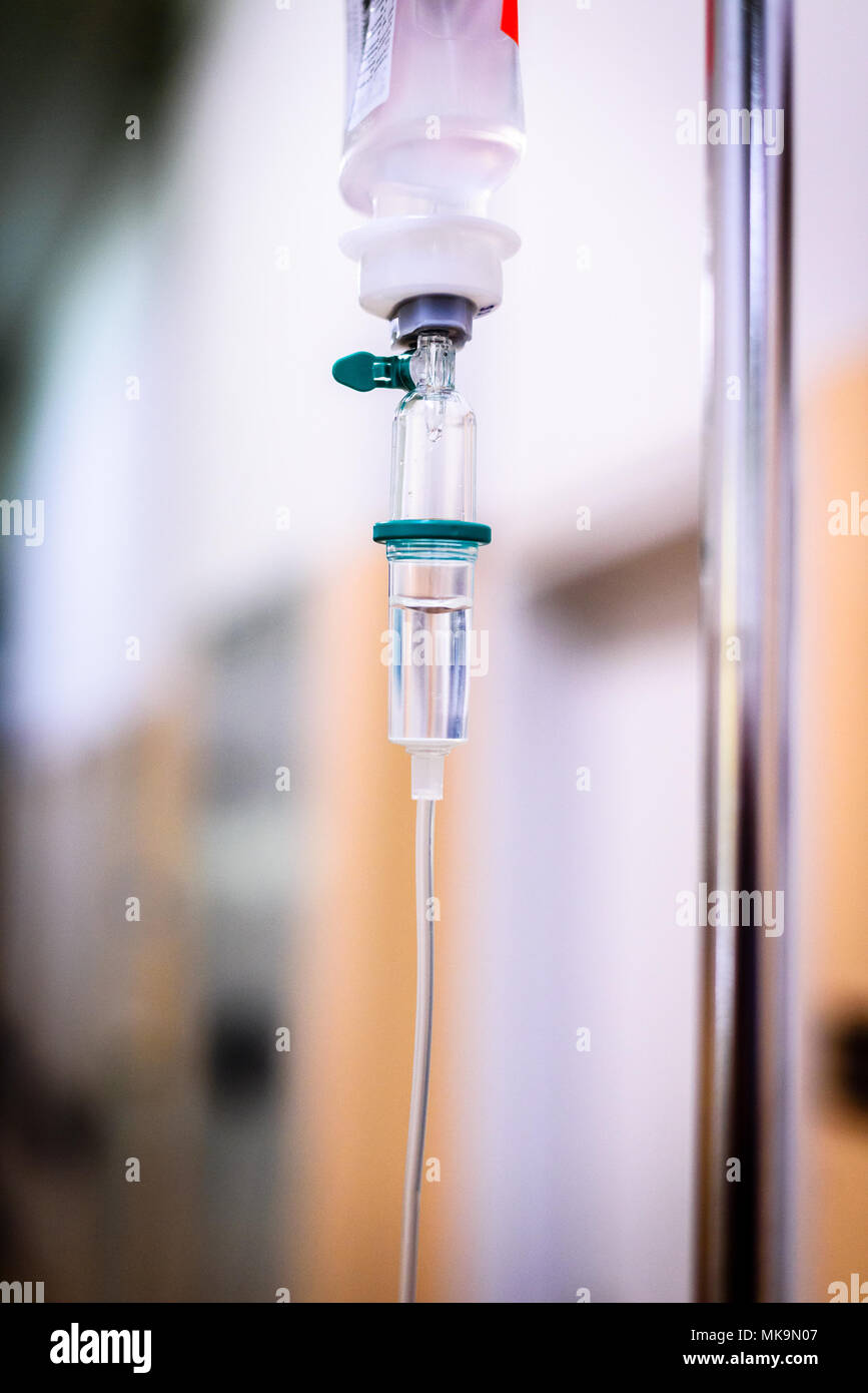 Mit der intravenösen Behandlung iv-Infusion und Flasche auf einer Stange. Flüssige Kochsalzlösung langsam Tropfen Tropfen Drogen, Arzneimittel oder antibiotische Therapie und Chirurgie Stockfoto