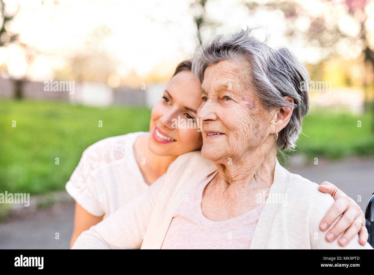 Ältere Großmutter und Enkelin umarmen im Frühjahr die Natur. Stockfoto