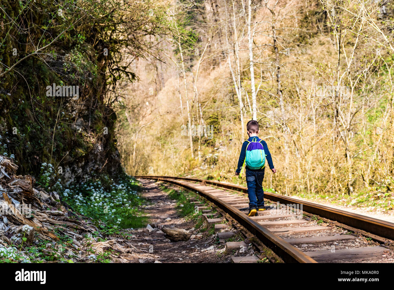 Junge Spaziergänge auf Bahngleise im Herbst Wald Stockfoto