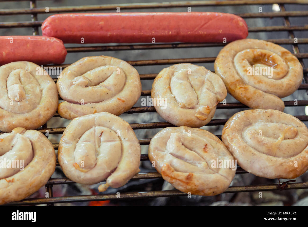 Würstchen auf dem Grill. Köstliche deutsche Würstchen oder Bratwurst auf dem Grill. Gegrillte Würstchen auf den brennenden Grill. Verschiedene Sorten von Würstchen Stockfoto