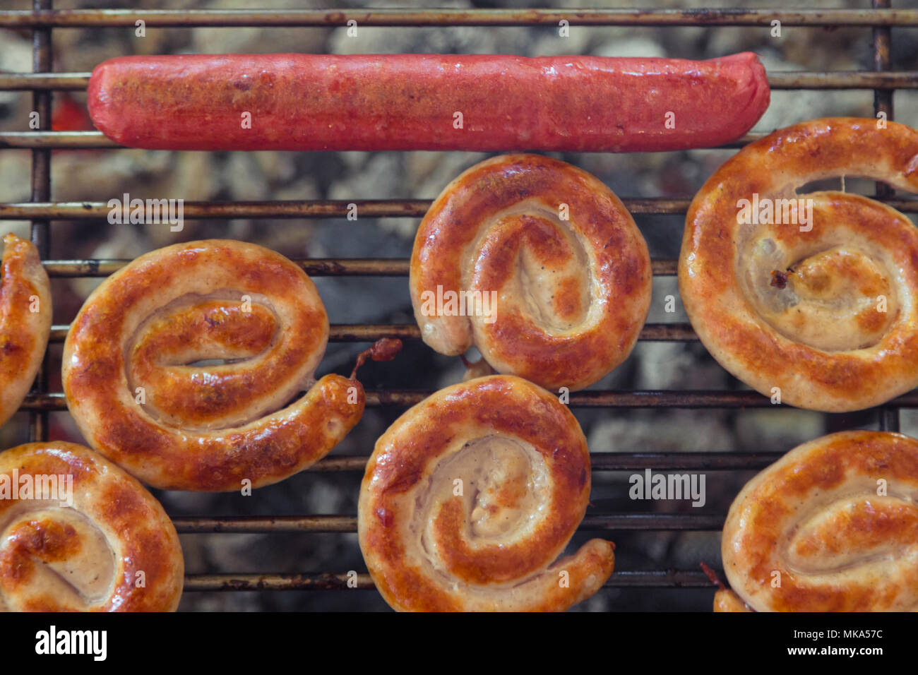 Grillen Würstchen am Grill zubereitet. Grill Würstchen auf dem Grill. Verschiedene Sorten von Würstchen auf dem Grill gebraten. Ansicht von oben. Stockfoto
