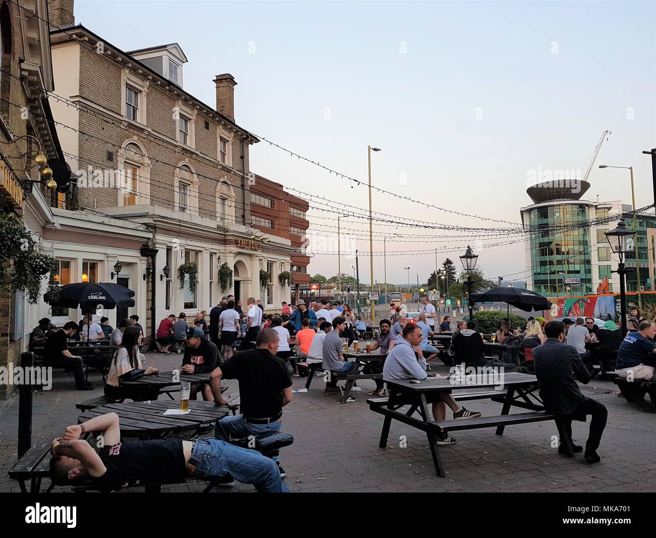 Die Menschen genießen den warmen Frühling Abend der May Bank Holiday außerhalb der Flagge Pub, Watford, UK Trinken und Geselligkeit, wie die Sonne untergeht. Stockfoto