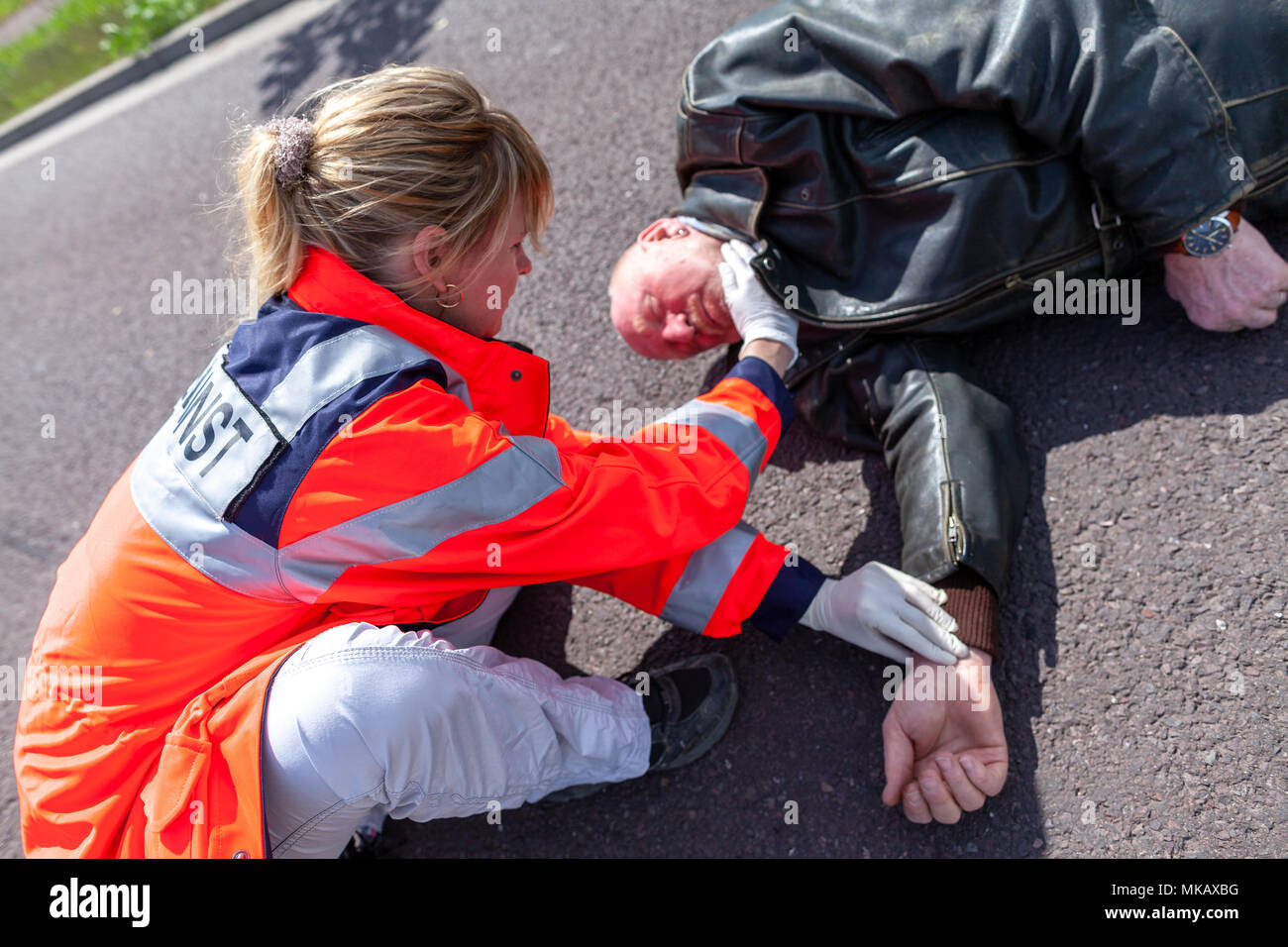 Ein deutscher Sanitäter prüfen Blutdruck auf eine verletzte Biker. Rettungsdienst ist das deutsche Wort für Krankenwagen. Stockfoto