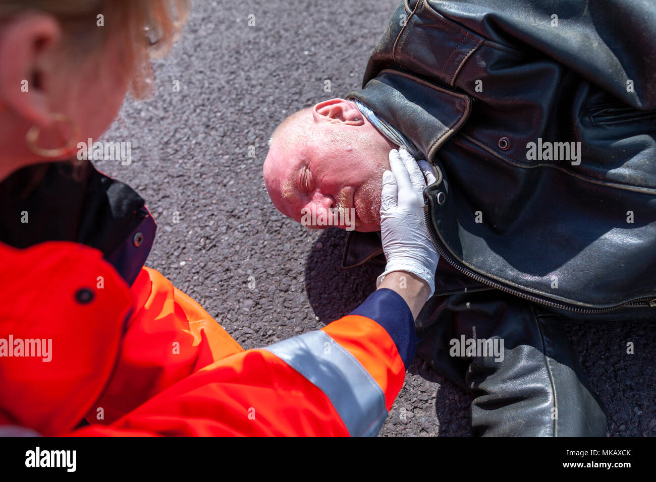 Ein deutscher Sanitäter prüfen Blutdruck auf eine verletzte Biker Stockfoto