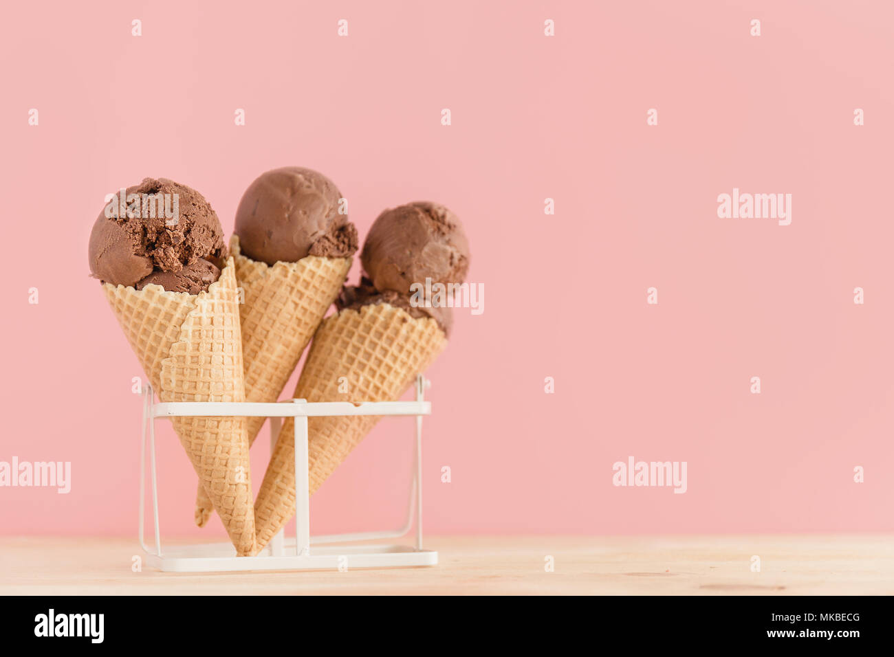 Köstliche Pastelltönen Schokolade Eis Kegel hinter zartes Rosa moderne Hintergrund. Horizontal mit Kopie Raum Stockfoto