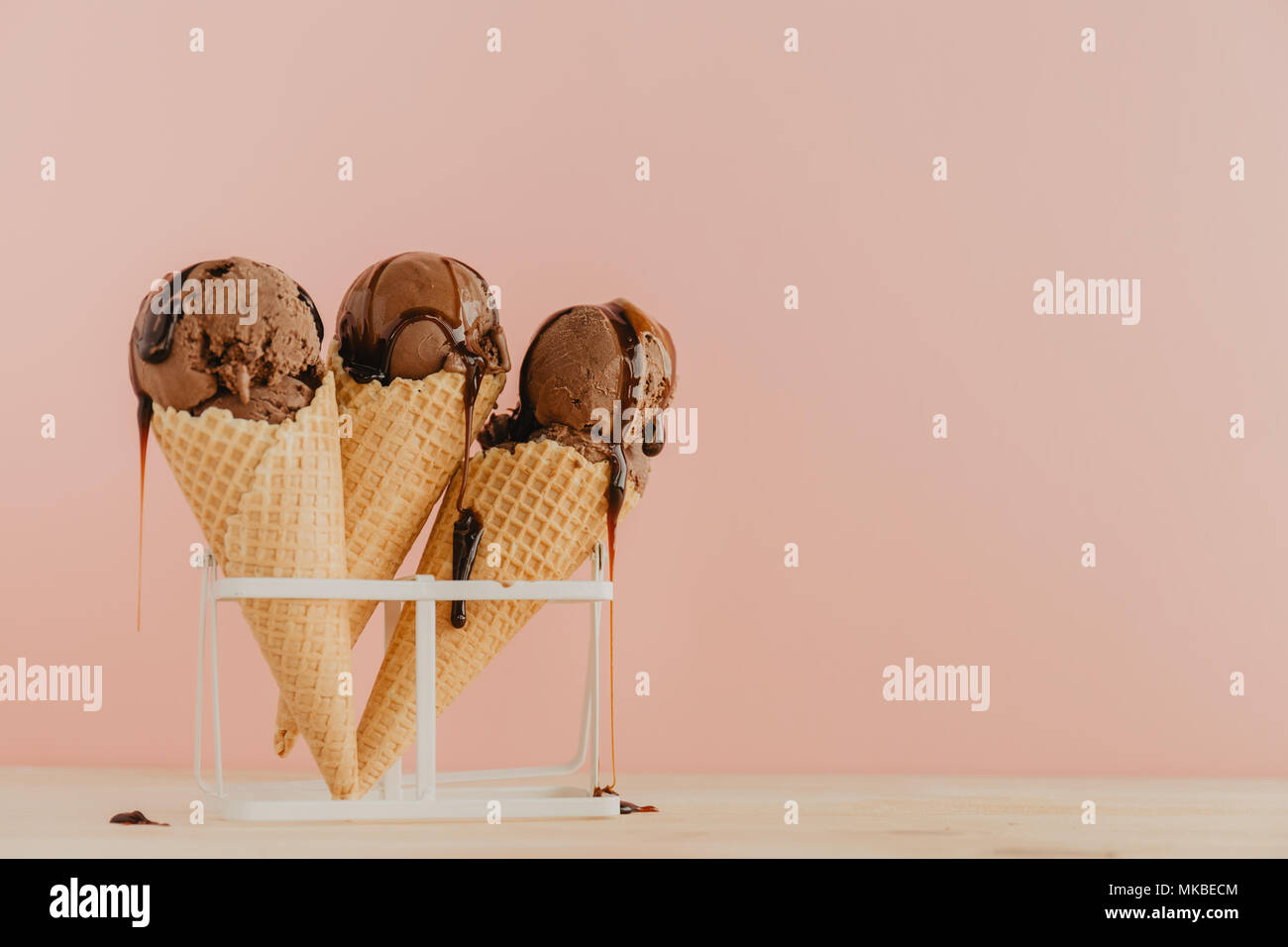Köstliche Pastelltönen Schokolade Eistüten mit Schokoladensauce hinter zartes Rosa moderne Hintergrund. Horizontal mit Kopie Raum Stockfoto