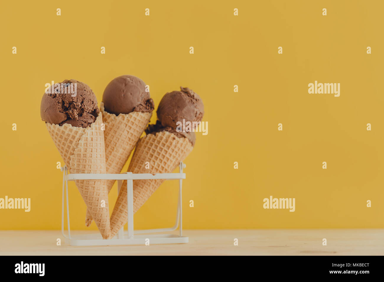 Köstliche Pastelltönen Schokolade Eis Kegel hinter zarten Gelb moderne Hintergrund. Horizontal mit Kopie Raum Stockfoto