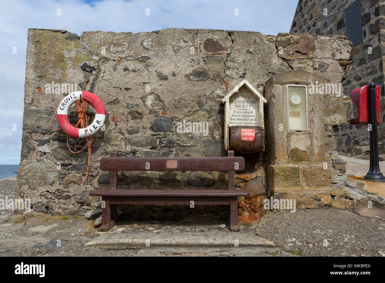 Sitz, Rettungsring, Barometer und Spende an der Pier, Crovie, Aberdeenshire, Schottland, Großbritannien Stockfoto