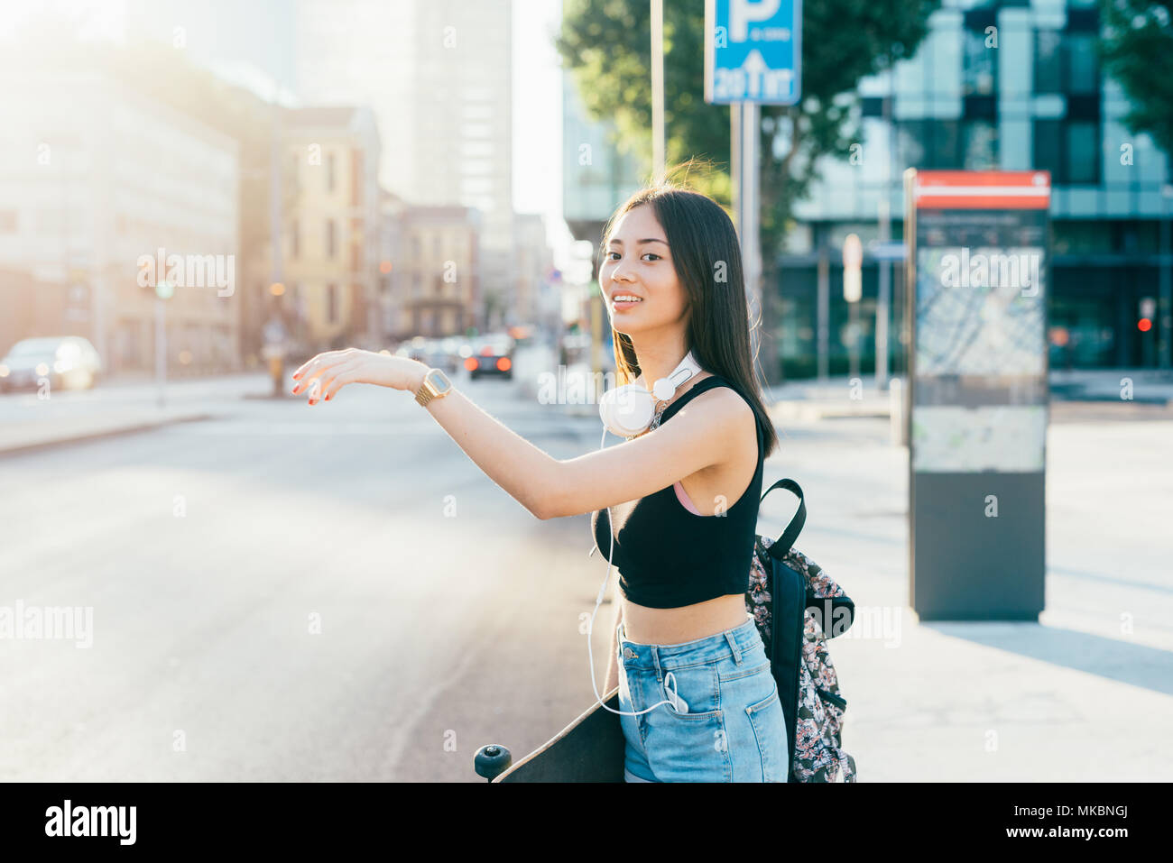 Die halbe Länge der jungen Hübschen asiatischen lange braune glatte Haare Frau wandern Outdoor in der Stadt, per Anhalter - Reisende, Verkehr Konzept Stockfoto