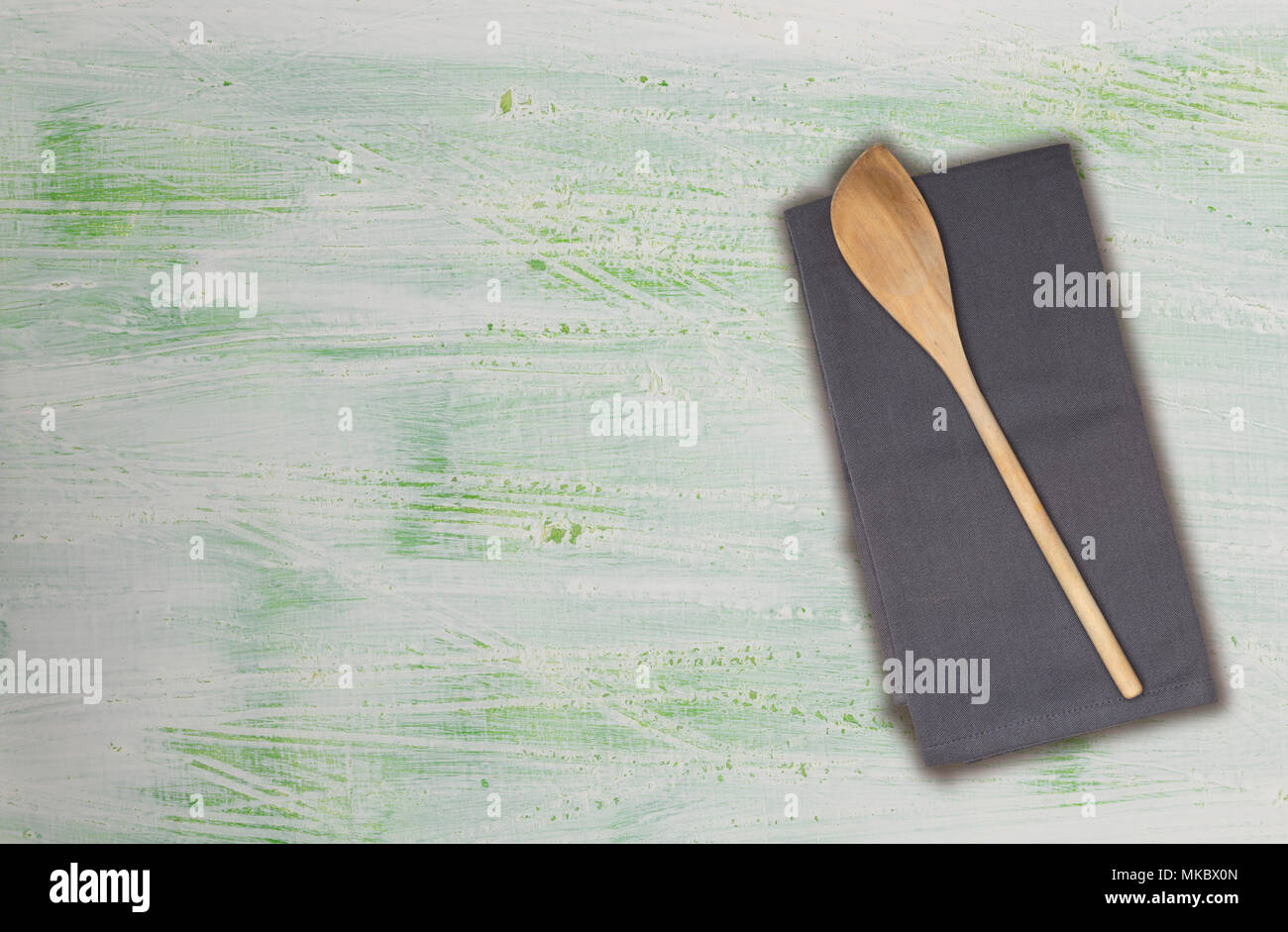 Holzlöffel und Küchentuch auf grün-weißen Holz. Stockfoto