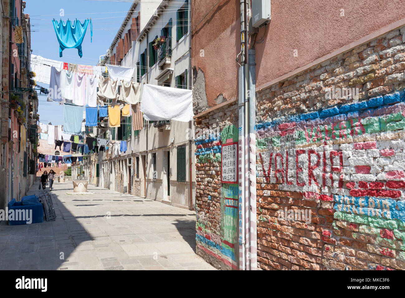 Washday in Castello, Venedig, Venetien, Italien mit Blick vorbei an bunten Graffiti auf einem Verwitterten Mauer der Kleidung hängen an Linien in einem campiello wi Stockfoto