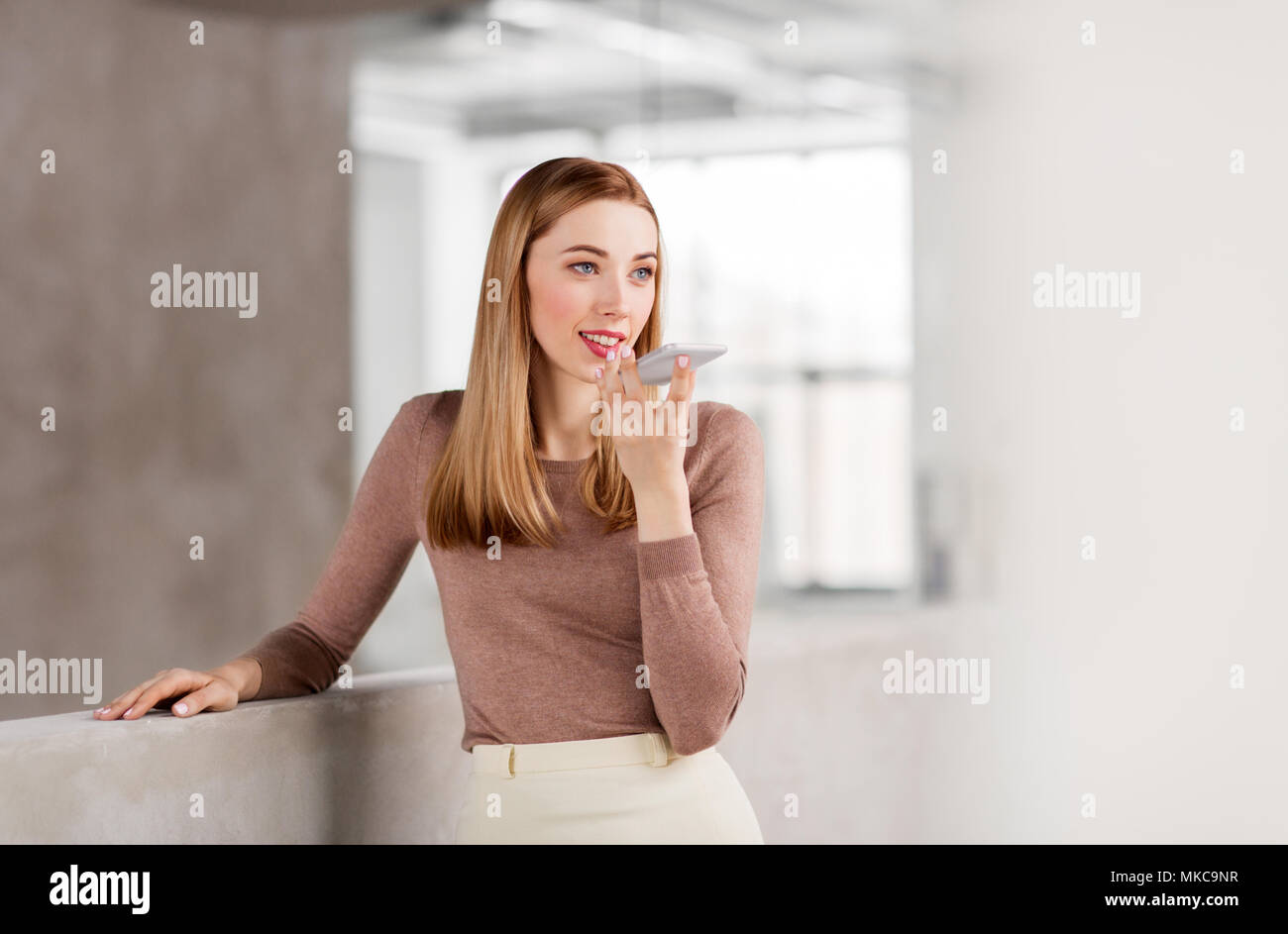 Frau mit Voice-Recorder auf Smartphone im Büro Stockfoto
