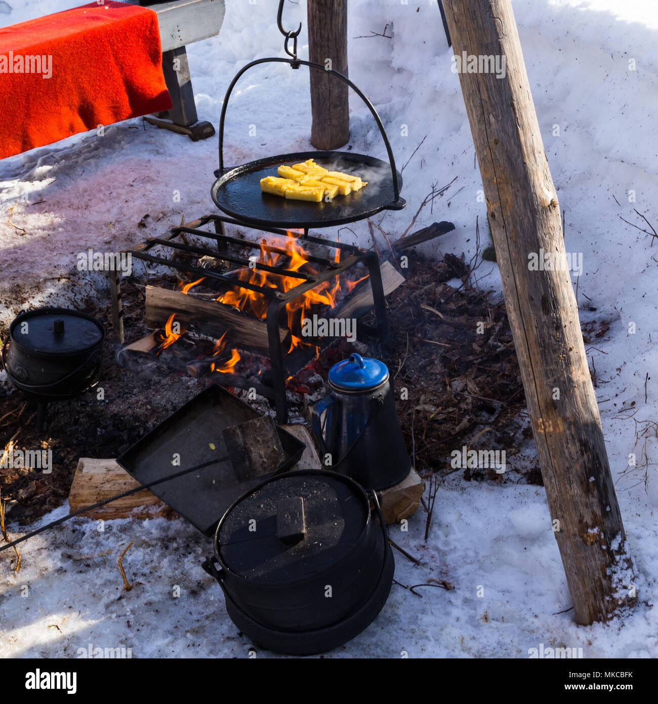 Kochen Frühstück über einem Feuer im Sugar Bush winter Encampment, Kings Landing Historical Settlement in New Brunswick, Kanada. Stockfoto