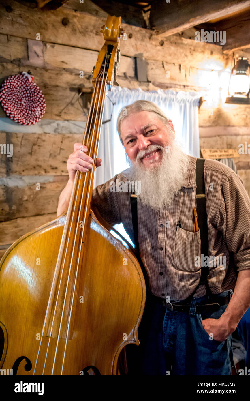Porträt einer Silver Dollar City Musiker Bass Player in den Ozarks Cabin mit weißen Bart lächelnd, Hosenträger. Berg Musik in Branson, Missouri, USA Stockfoto