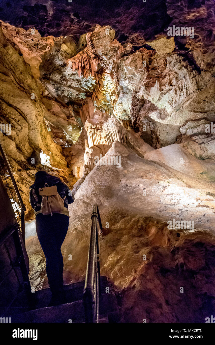 Marvel Höhle unter Silver Dollar City in Branson, Missouri; eine weibliche Wanderer mit Rucksack Handtasche klettert steile Treppen durch Kalkstein Höhle auf Tour. Stockfoto