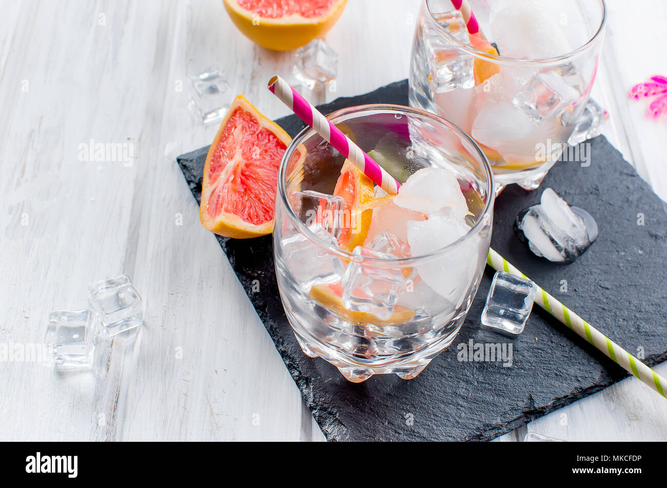 Glas mit Grapefruit Schichten und Eis, Kochen grapefruit Cocktail, Zutaten für ein Getränk auf weiße Holztisch, kopieren Raum Stockfoto