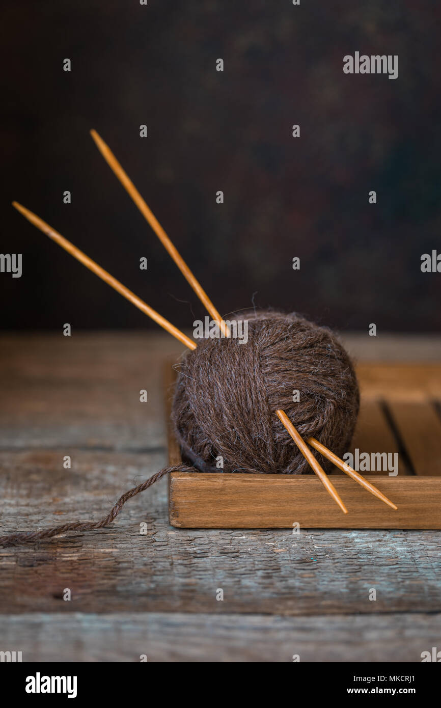 Wolle Garn mit Nadeln auf einem urigen Hintergrund, Herbst Wabi Sabi Konzept, getönt Stockfoto