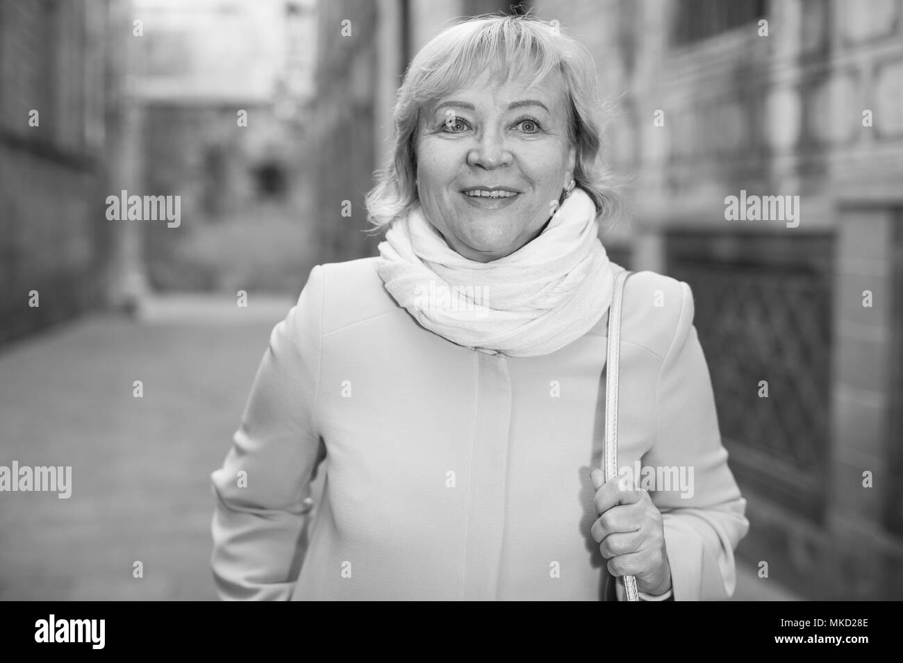 Fröhliche erwachsene Frau in Schal an der Straße im Herbst Stockfoto