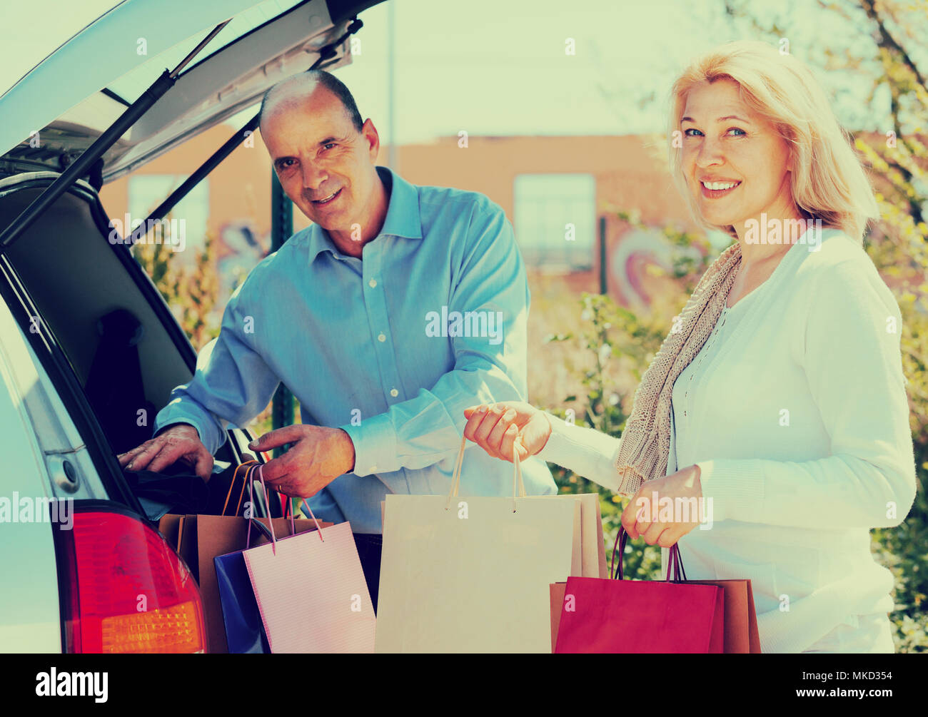 Älterer Mann und Frau setzen Taschen mit Einkäufe im Kofferraum eines Autos Stockfoto