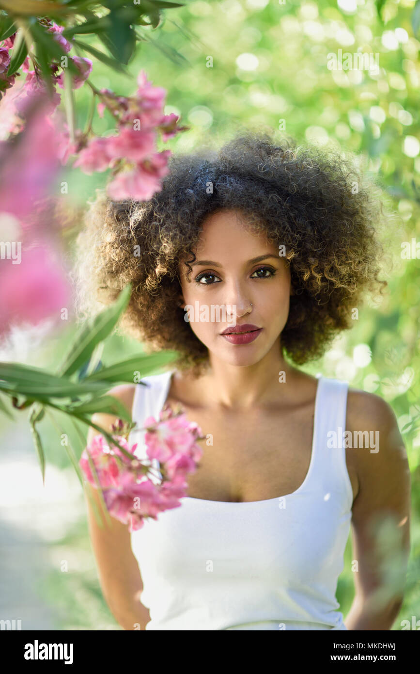 Junge Schwarze Frau Mit Afro Frisur Im Stadtischen Park Gemischte Madchen Legere Kleidung Zwischen Rosa Bluten Stockfotografie Alamy alamy