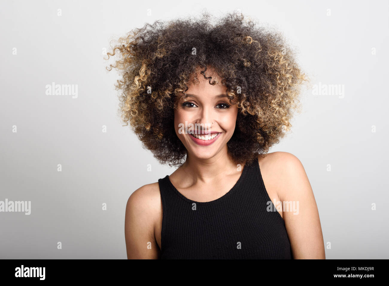 Junge schwarze Frau mit Afro Frisur lächelnd. Mädchen mit schwarzen Kleid. Studio gedreht. Stockfoto