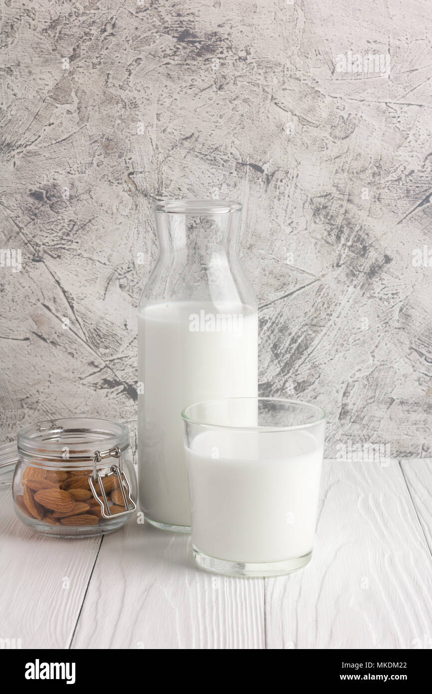 Flasche Mandelmilch mit Glas und Mandeln in jar auf rustikalen weiße Holztisch. Vertikale Ausrichtung Stockfoto