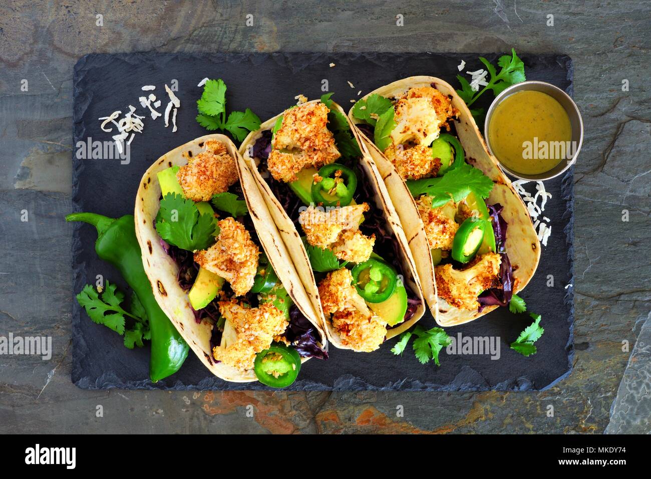 Roasted Coconut Blumenkohl Tacos. Gesunde, vegane Mahlzeit. Oben Blick auf dunklem Schiefer Hintergrund. Stockfoto