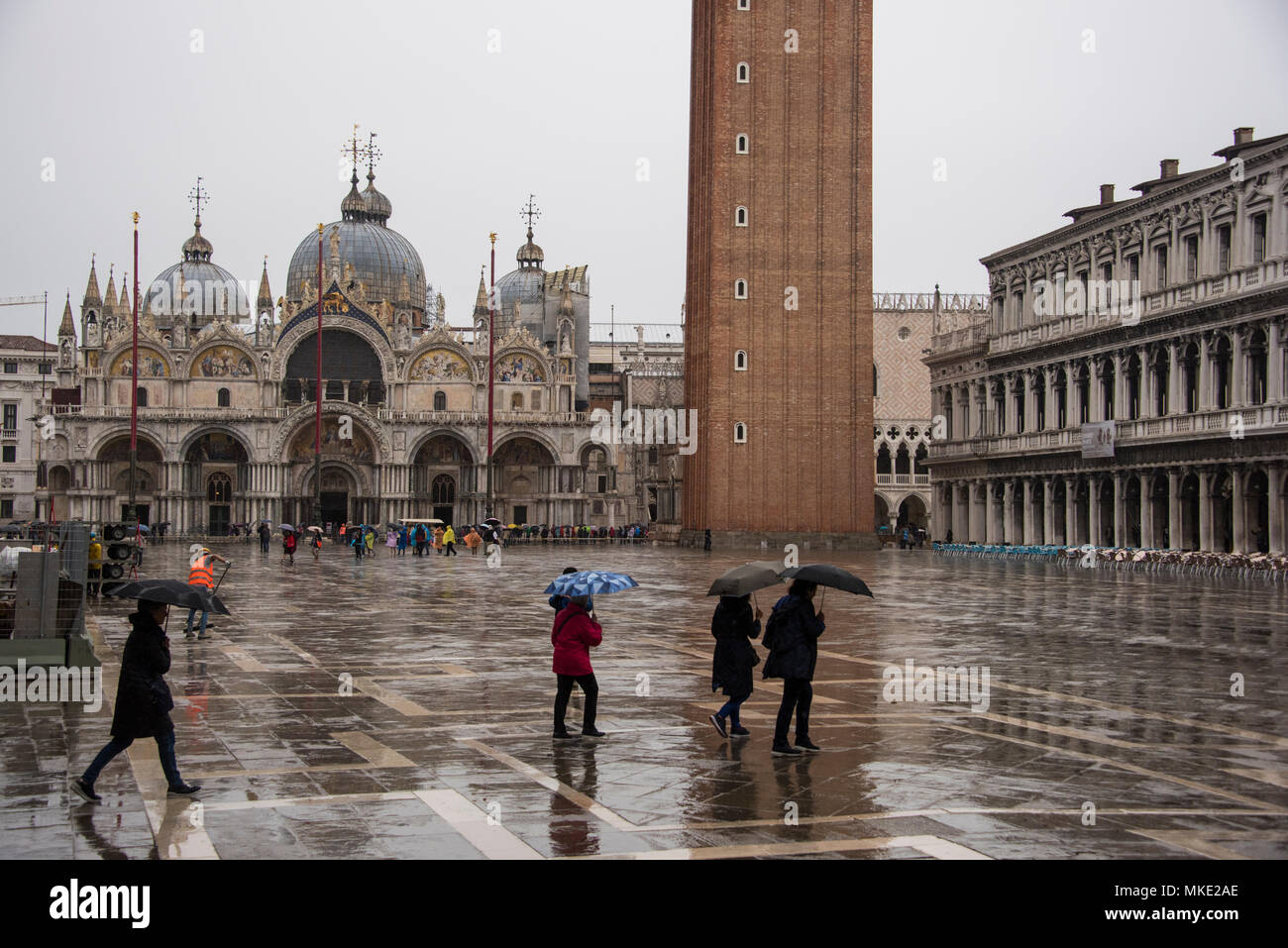 Touristen Kreuzung St. Markusplatz mit Sonnenschirmen im Regen, Venedig Stockfoto