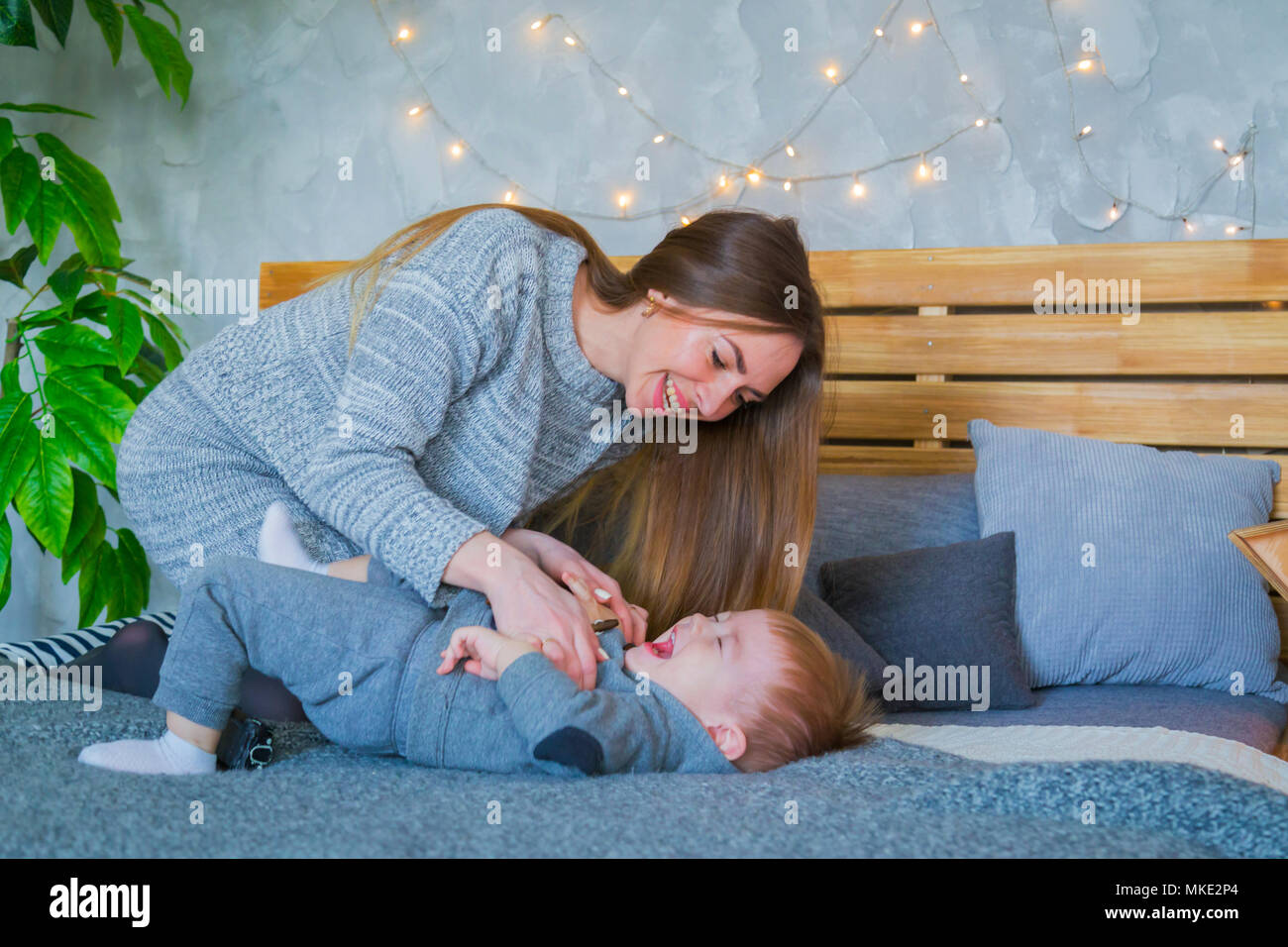 Glückliche junge Mutter und ihr Baby Sohn spielen Togerher Stockfoto
