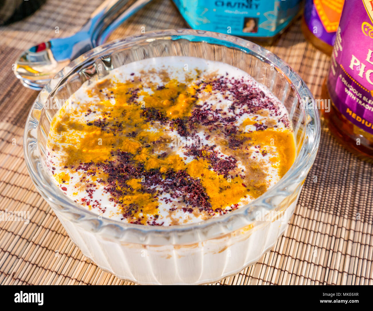 Close up Outdoor-Tisch-Set zum Servieren von Curry mit Begleitung von Joghurt mit Gewürzen, Chutney und Limetteneingelegter, Vereinigtes Königreich Stockfoto