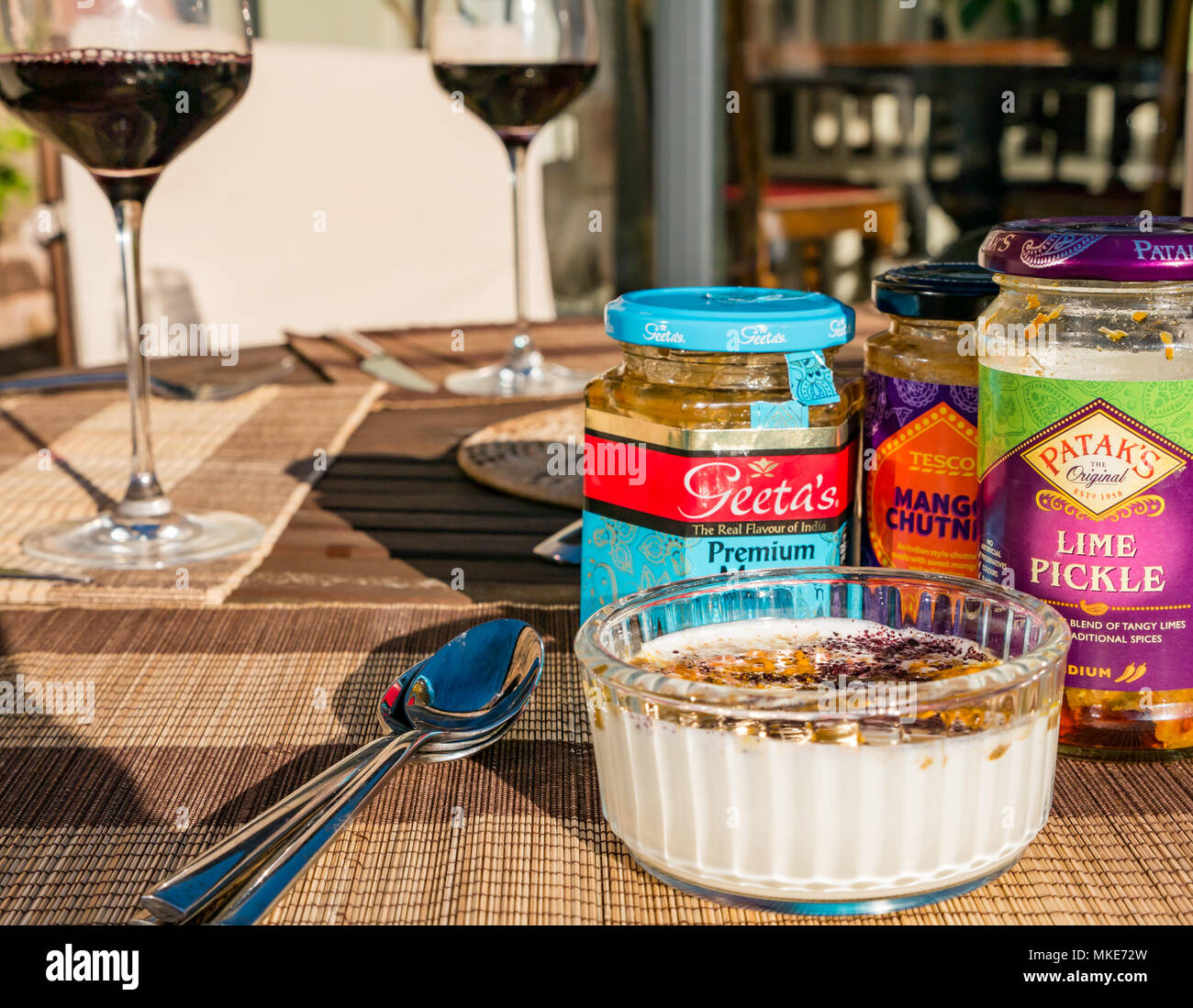 Tisch im Freien zum Servieren mit Begleitungen Joghurt, aromatisiert mit Gewürzen, Chutney und essiggurke Gläser Curry und roten Wein in Gläsern, Schottland, Großbritannien Stockfoto