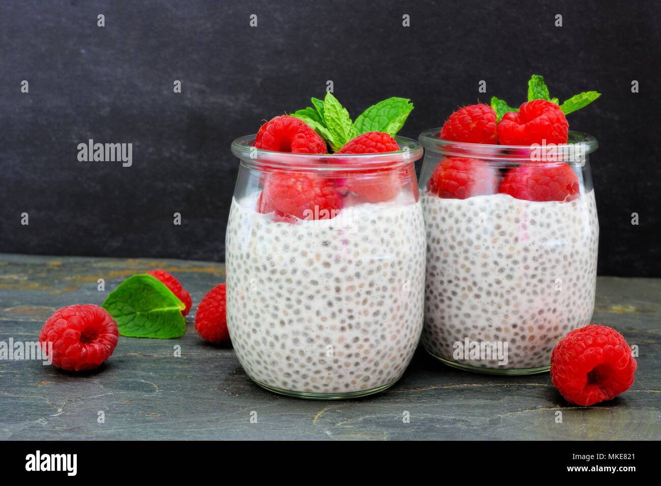 Gesunde Himbeere chia Pudding in Gläsern. Szene mit einem dunklen Stein Hintergrund. Stockfoto