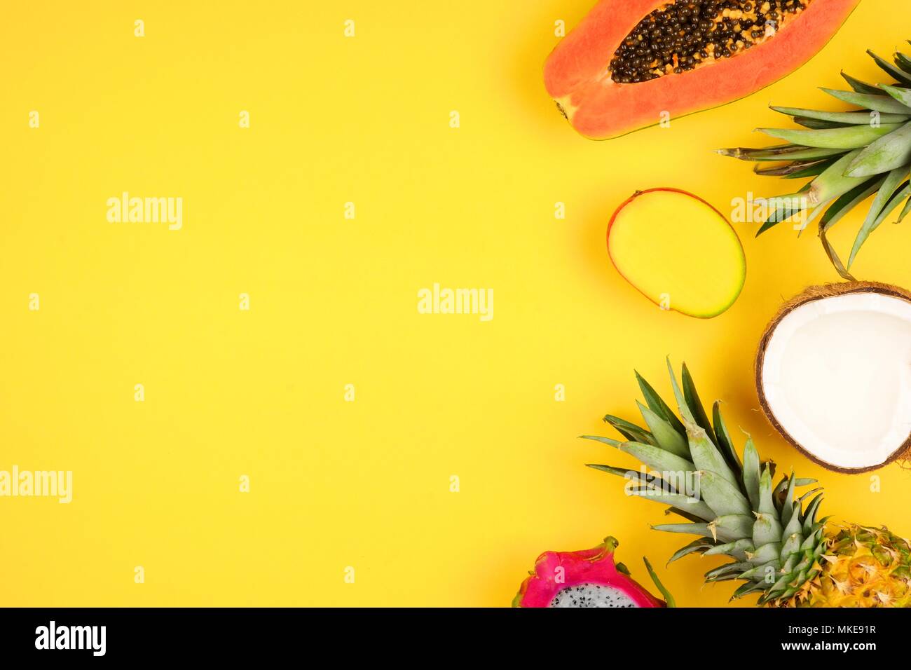 Tropische Früchte Seite Grenze mit Ananas, Drachenfrucht, Papaya, Kokos und Mango auf einem hellen gelben Hintergrund Stockfoto
