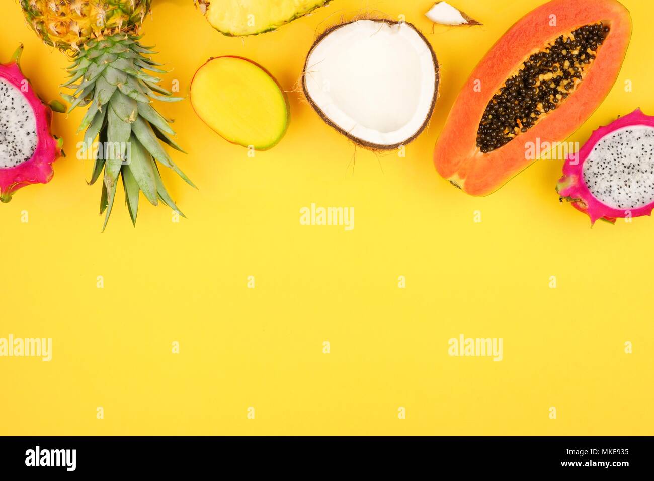 Tropische Früchte oberer Rand mit Ananas, Drachenfrucht, Papaya, Kokos und Mango auf einem hellen gelben Hintergrund Stockfoto