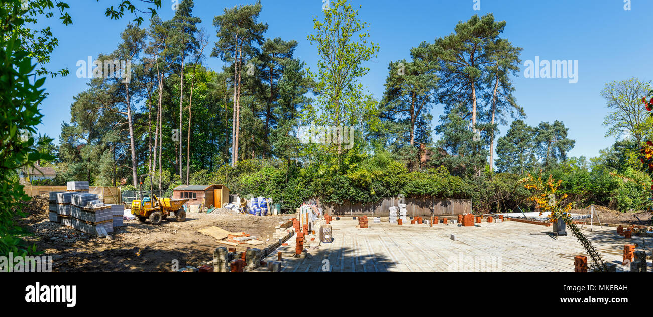 Ansicht einer vorstädtischen Wohnviertel Baustelle für ein neues Haus auf einer Brachfläche mit Baumaterialien und Kipper an einem sonnigen Tag Stockfoto