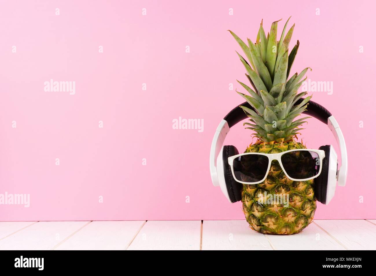 Hipster Ananas mit Sonnenbrille und Kopfhörer vor einem rosa Hintergrund. Minimale Sommer Konzept. Stockfoto