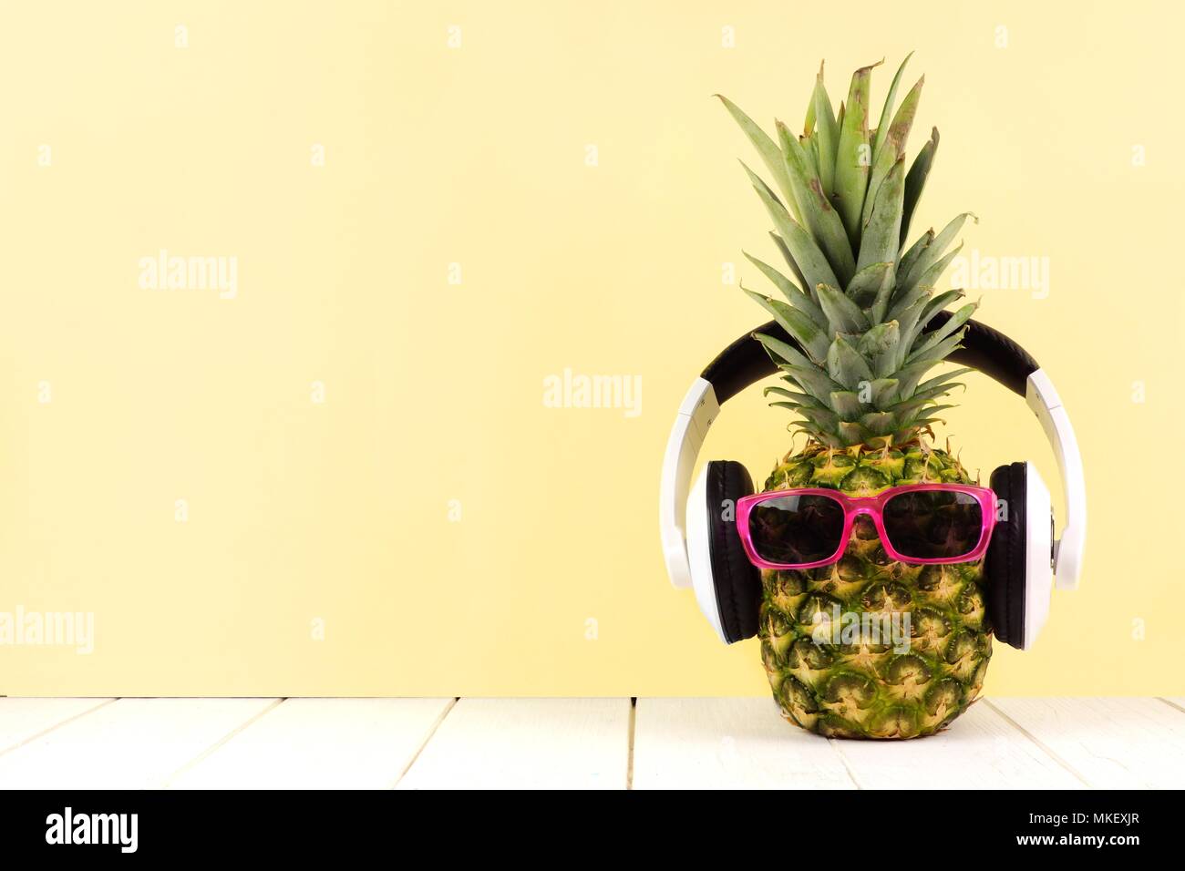 Hipster Ananas mit Sonnenbrille und Kopfhörer vor einem gelben Hintergrund. Minimale Sommer Konzept. Stockfoto