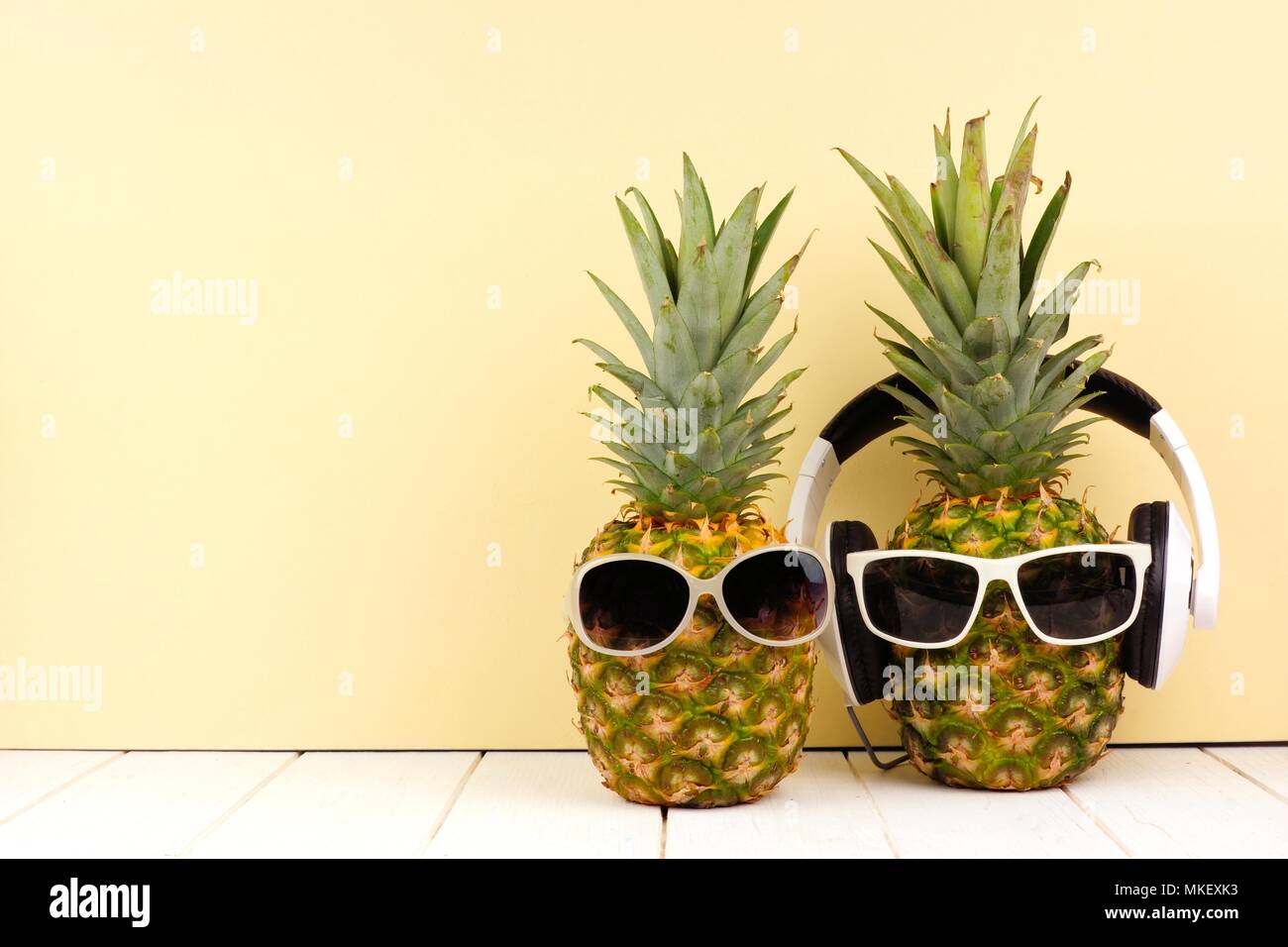 Hipster Ananas mit Sonnenbrille und Kopfhörer vor einem gelben Hintergrund. Minimale Sommer Konzept. Stockfoto