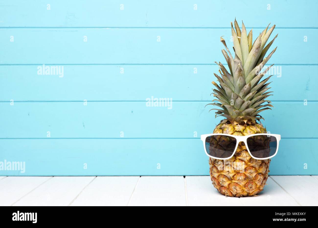 Hipster Ananas mit Sonnenbrille vor einem blauen Hintergrund aus Holz Stockfoto