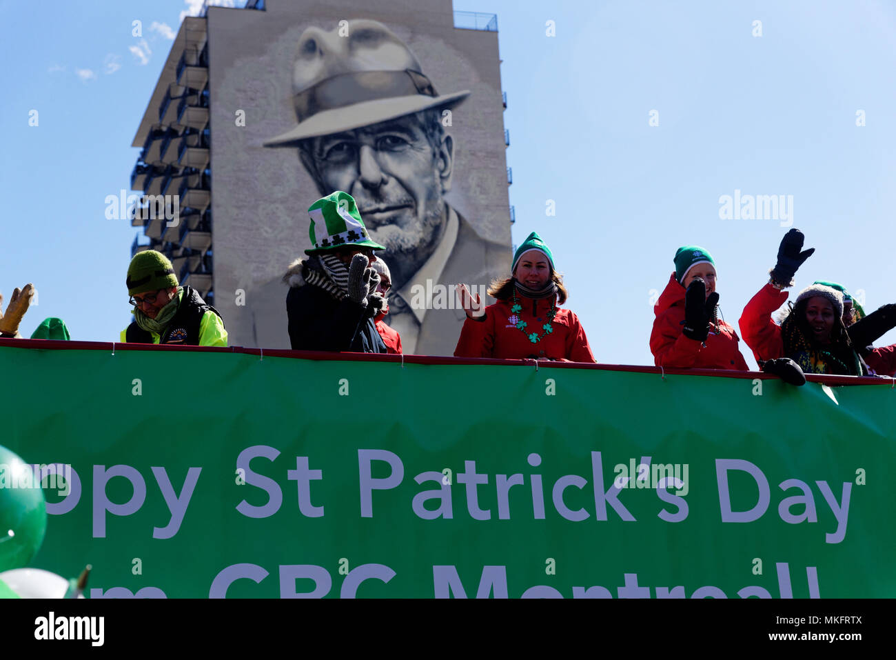 Montreal St. Patricks Day Parade Teilnehmer winken von der Spitze eines Londoner Routemaster Double Decker Bus mit dem Portrait von Leonard Cohen hinter Stockfoto