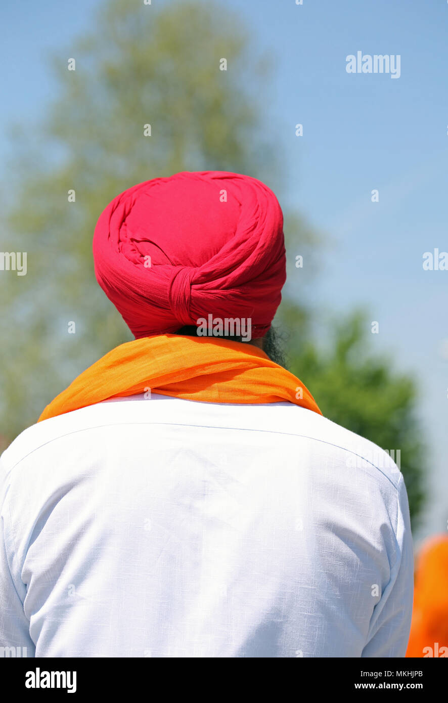 Mann mit roten Turban weißes Hemd und Schal orange von hinten Stockfoto