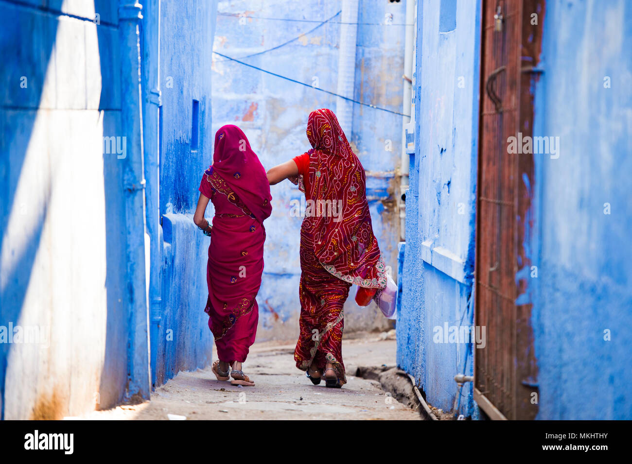 Zwei Frauen in der traditionellen indischen Sari gekleidet sind ein Spaziergang durch die engen Gassen von die blaue Stadt Jodhpur, Rajasthan, Indien. Stockfoto
