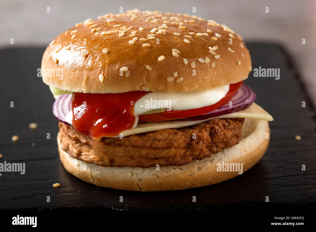 Nahaufnahme von einem Cheeseburger mit Tomaten und Mayonnaise Soße auf Schiefer Stockfoto