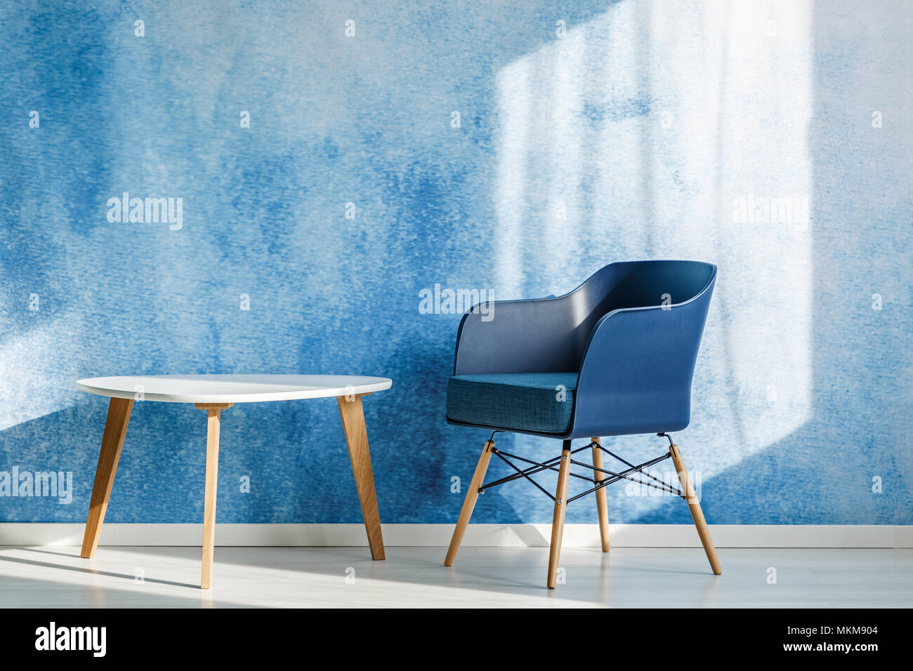 Marine Blau Sessel neben weiße Holztisch in minimalen Wohnzimmer Innenraum Stockfoto