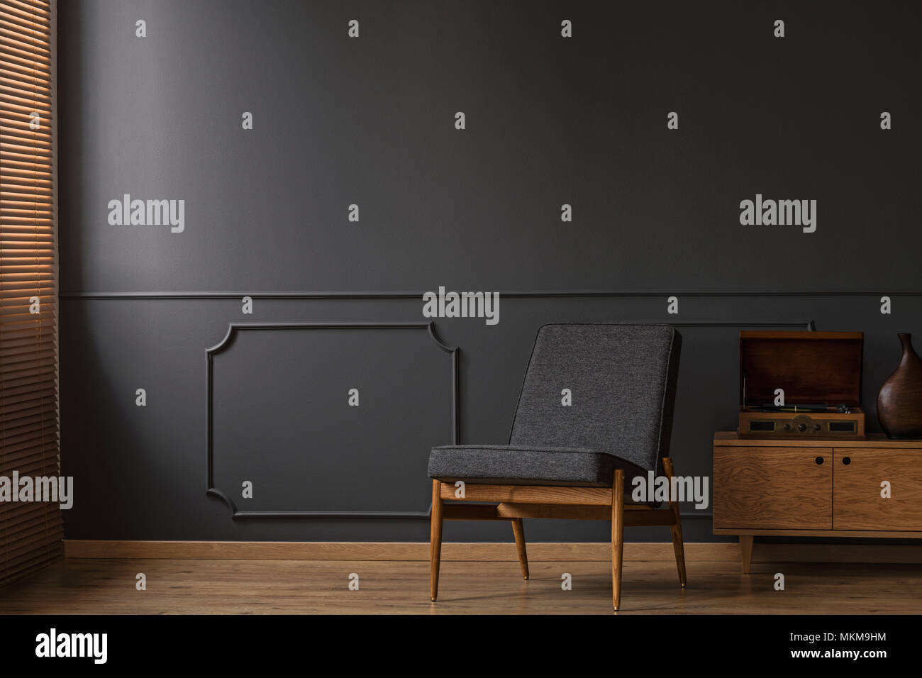 Grau Sessel auf die graue leere Wand mit Spritzguss im Wohnzimmer Einrichtung mit Holzboden Stockfoto