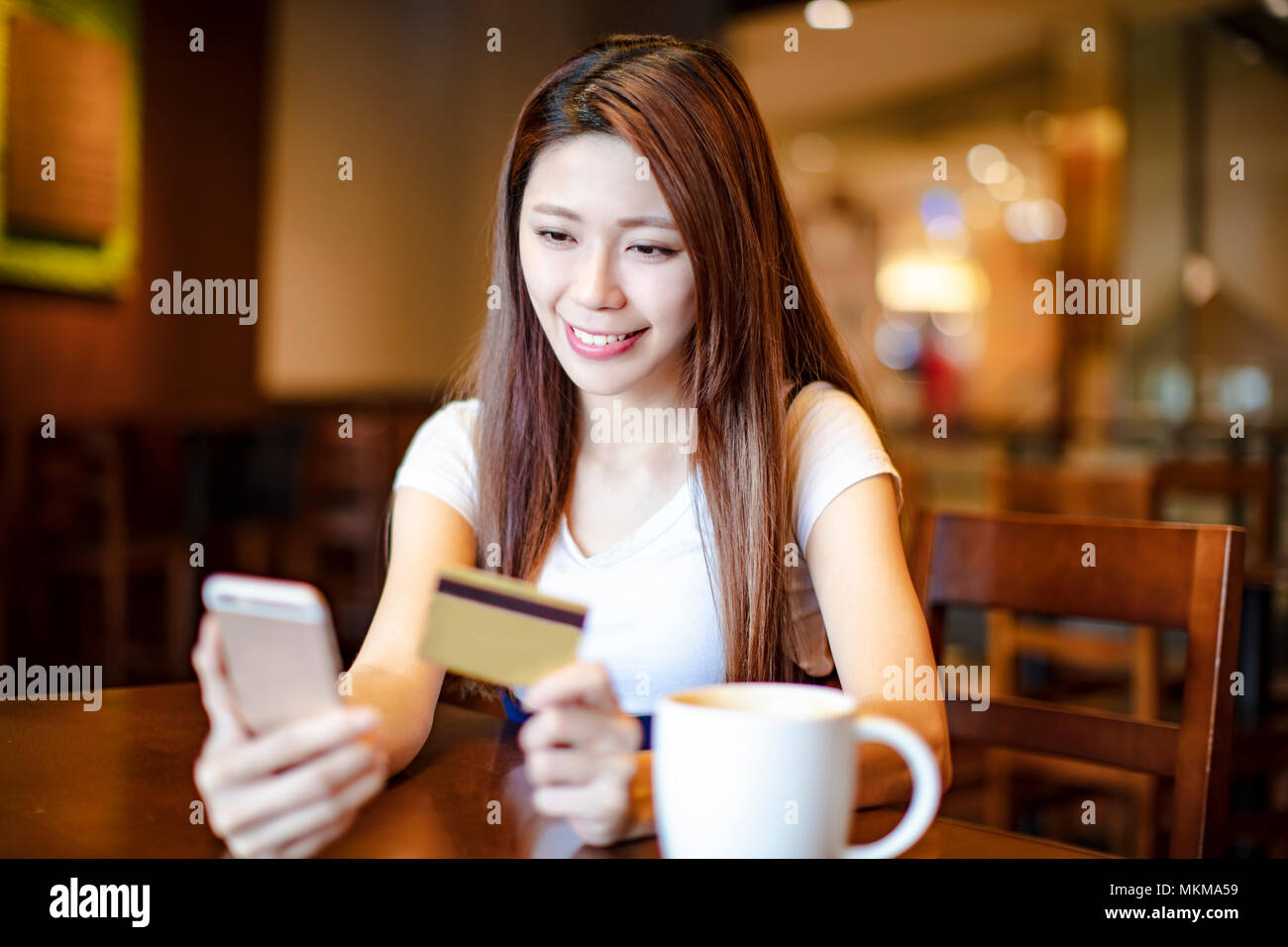 Frau mit Kreditkarte und Smart Phone in Coffee Shop Stockfoto