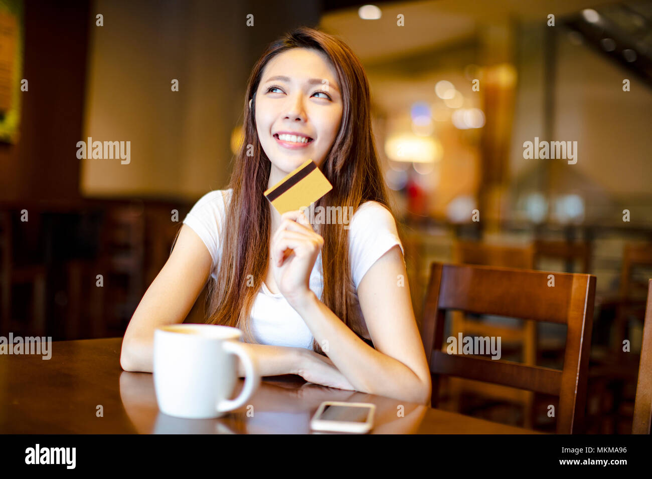 Junge Frau mit Kreditkarte und Denken Stockfoto