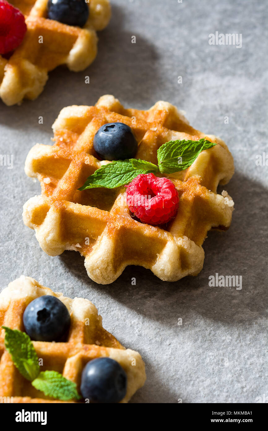 Traditionelle belgische Waffeln mit Heidelbeeren und Himbeeren auf grauem Stein Stockfoto